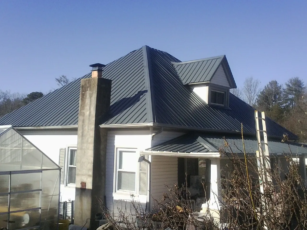 Dark blue standing seam metal roof on a white farmhouse with dormer — Slate & Tile Roof Repair by Roofing Brothers in Lebo