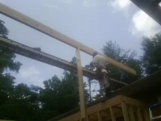 Carpenter setting a ridge beam over a new addition frame — Ice Dam Removal by Roofing Brothers in Lebo