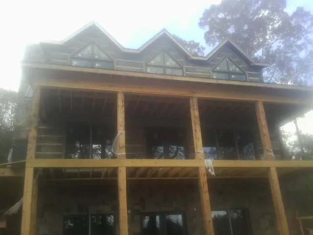Dormers and porch framing on a large log home under construction — Roof Coating work by our crew in Lebo