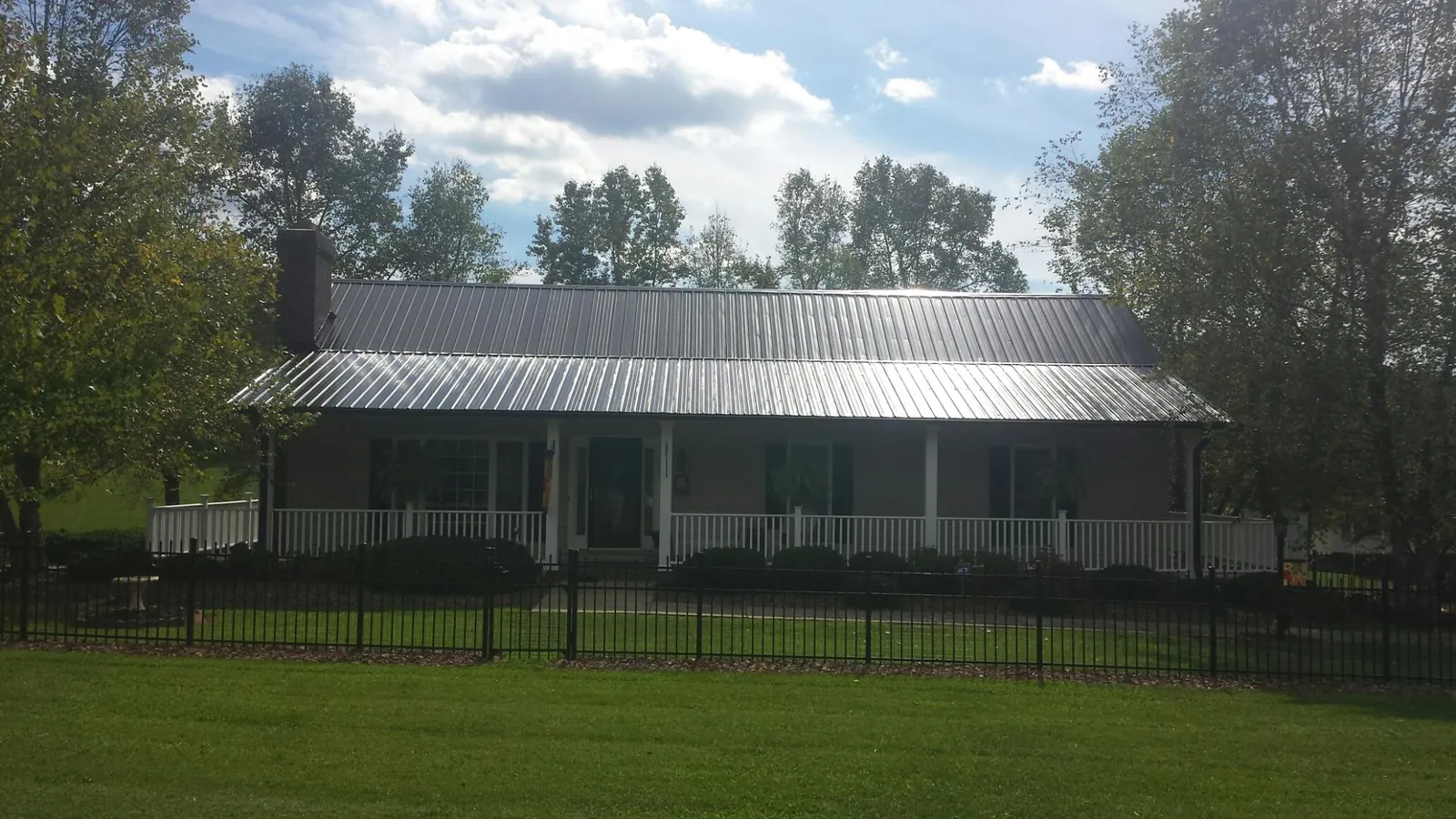 Gray metal roof on a brick ranch with a full width front porch — Gutter Guard Installation work by our crew in Lebo