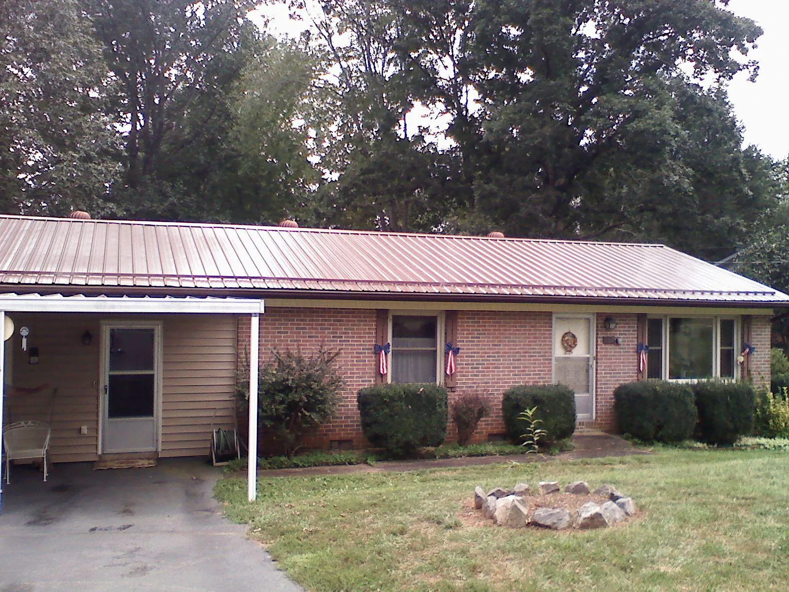 Bronze metal roof and carport on a brick ranch home — Roof Repair work by our crew in Lebo