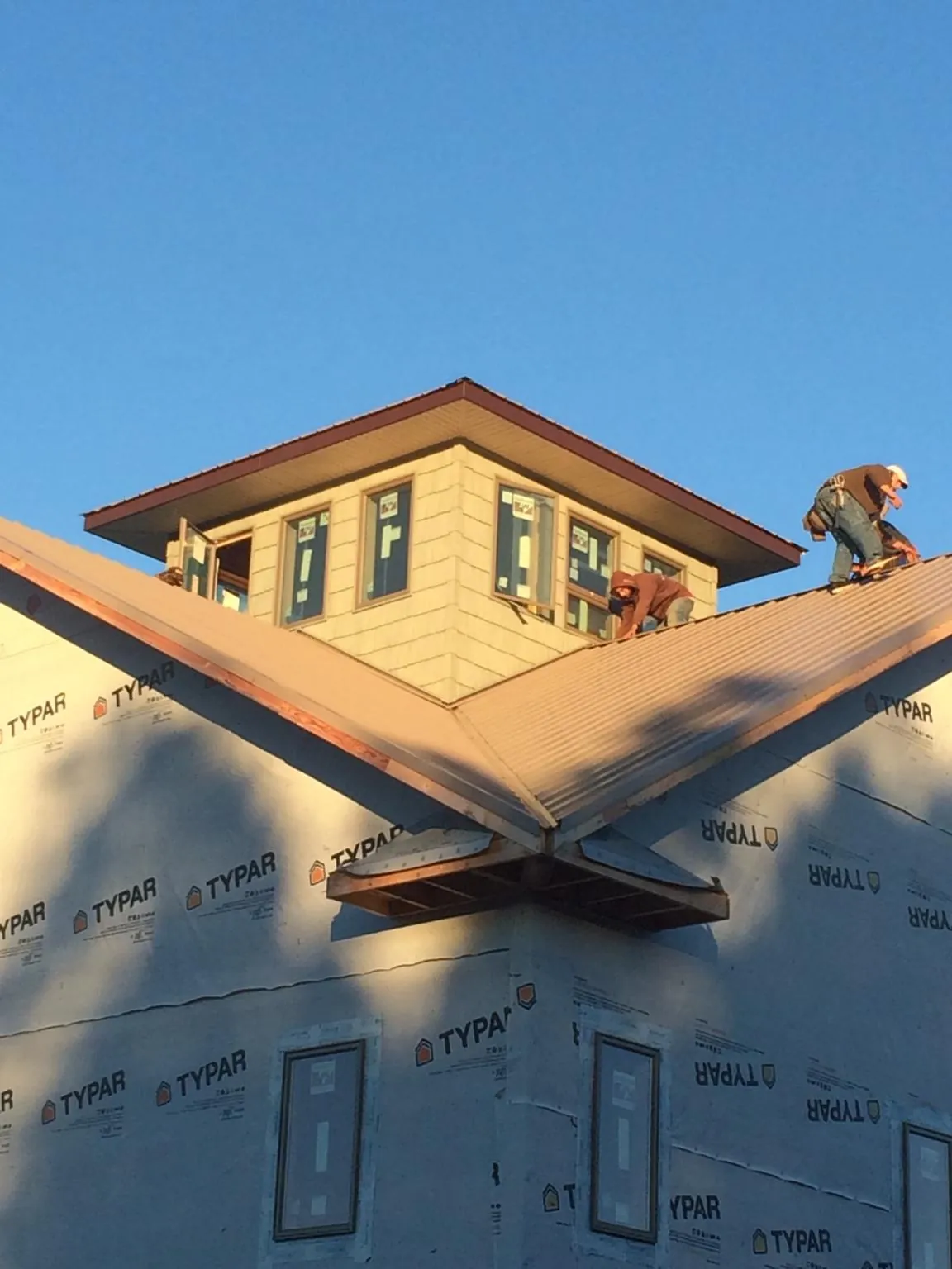 Roofers working around a rooftop cupola on a new metal roof at sunset — Roof Waterproofing in Lebo by Roofing Brothers